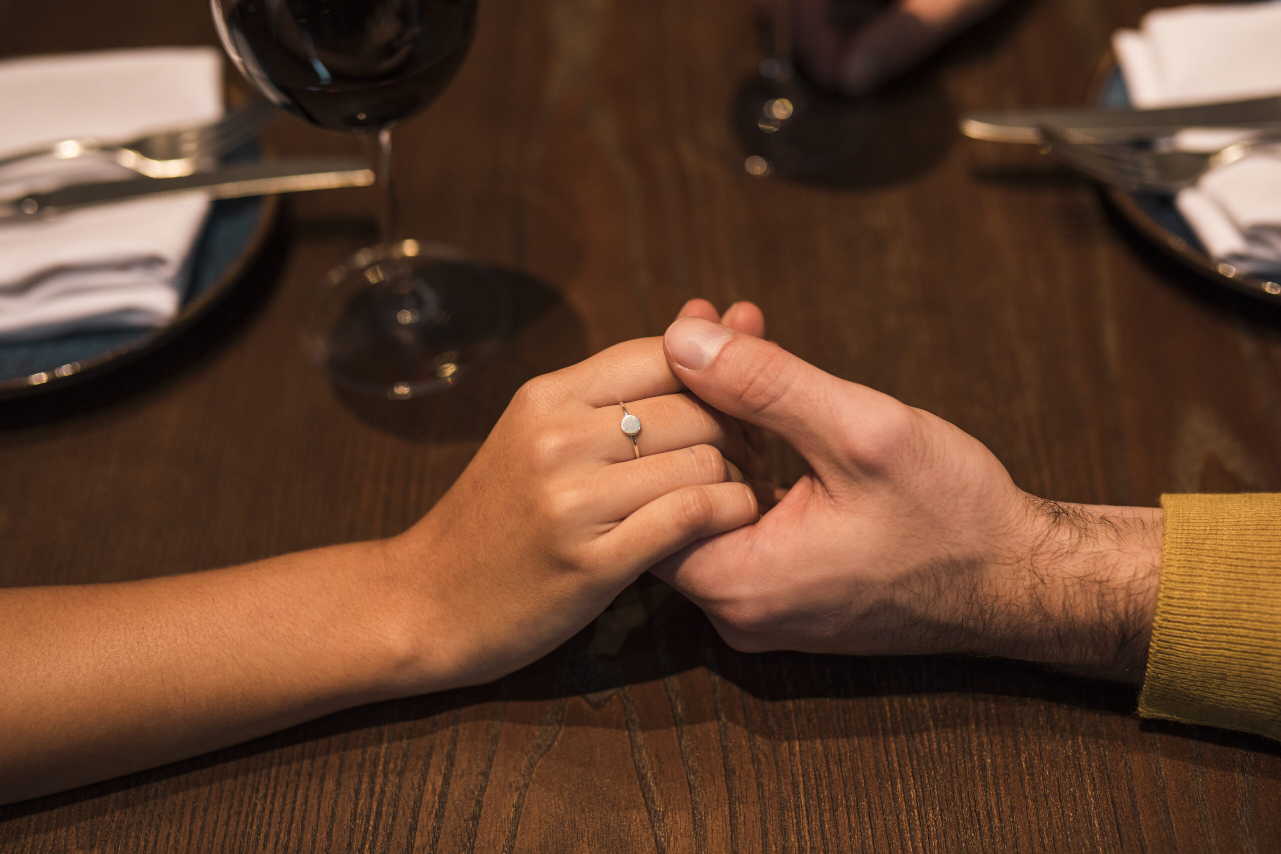 Detalhe de um casal de mãos dadas, simbolizando a união.