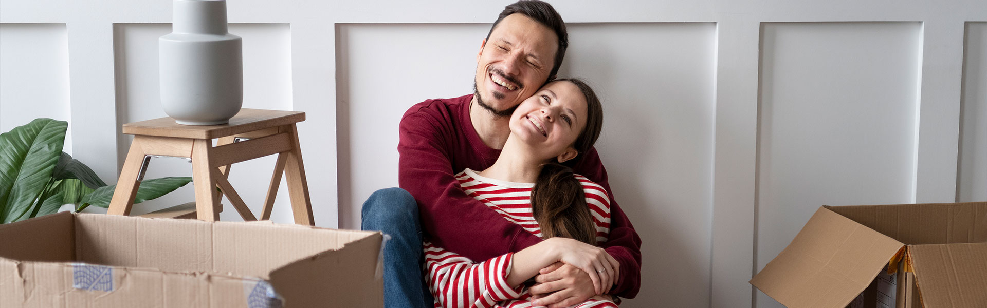 Casal sorrindo sentado na sala do apartamento novo da Quartzo